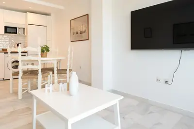 a living room with a white table and a tv at Apartoyou - Vistahermosa Bahía in El Puerto de Santa María
