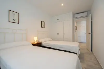 two beds in a bedroom with white walls at Apartoyou - Vistahermosa Bahía in El Puerto de Santa María