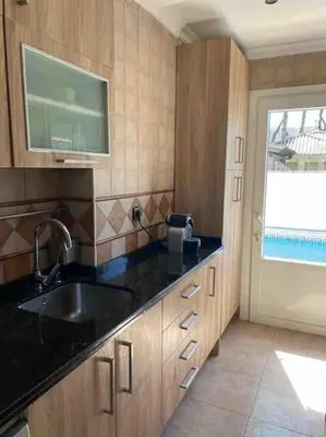 a kitchen with wooden cabinets and a sink and a window at Villa Verde con Piscina a 800m de la Playa by Chiclana Dreams in Chiclana de la Frontera