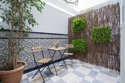 a table and chairs on a patio with a wall at Aire del Sur Cádiz in Cádiz
