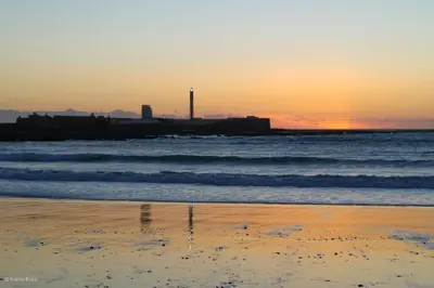 a sunset on the beach with the ocean at Aire del Sur Cádiz in Cádiz
