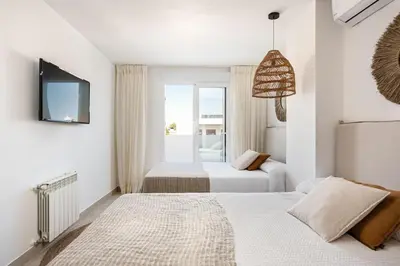 a white bedroom with two beds and a television at Ocean beachside house with pool 46 in Conil de la Frontera