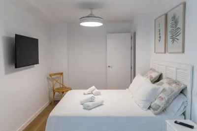 a white bedroom with a bed and a tv at Zurbarán by Gades Gestión in Cádiz