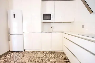 a kitchen with white cabinets and a refrigerator at GuestReady - Sanlucar Piletas Beach in Sanlúcar de Barrameda