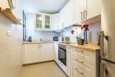a white kitchen with white cabinets and flowers on the counter at Cruz Vieja Centrico 3 Rooms in Jerez de la Frontera