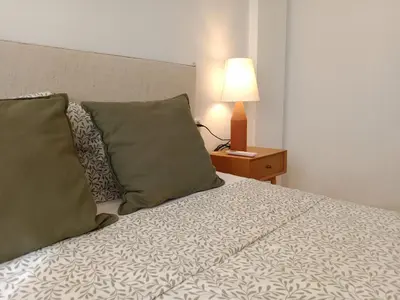 a bed with two pillows and a lamp on a table at Dúplex Apartment Sol de la Plazuela in Jerez de la Frontera