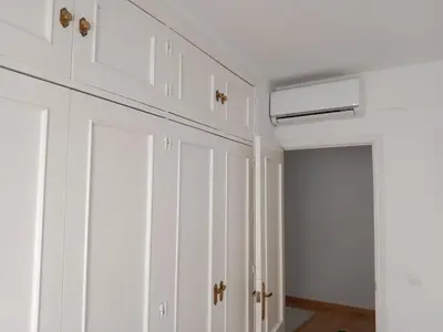 a white kitchen with white cabinets and a hallway at Dúplex Apartment Sol de la Plazuela in Jerez de la Frontera
