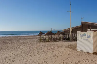 a beach with some tables and umbrellas and the ocean at PUERTA del MAR Family Home by Cadiz4Rentals in Cádiz