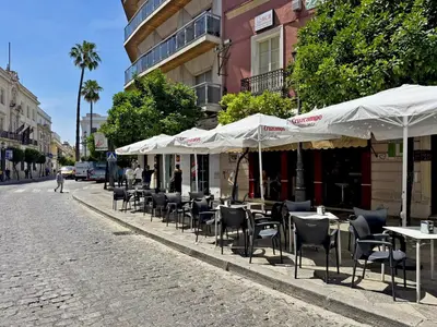 a row of tables and chairs with umbrellas on a street at Apartamento Larga 65 - Ole Solutions in Jerez de la Frontera