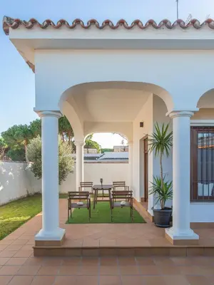a patio with a table and chairs under a white house at VILLA DE LUJO CLIMATIZADA. PISCINA Y JARDIN PRIVADO in Chiclana de la Frontera