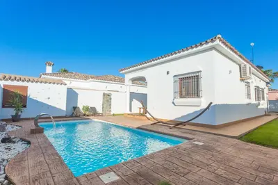 a villa with a swimming pool in front of a house at VILLA DE LUJO CLIMATIZADA. PISCINA Y JARDIN PRIVADO in Chiclana de la Frontera