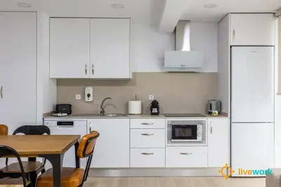 a kitchen with white cabinets and a table at Travelers Dream by LiveWork in Cádiz