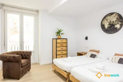 a bedroom with two beds and a chair at Travelers Dream by LiveWork in Cádiz