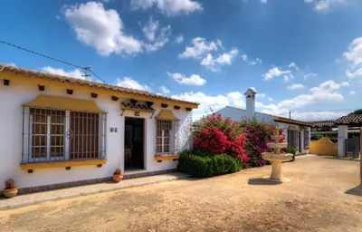 a white house with a fountain in the yard at Hacienda los Majadales in Conil de la Frontera