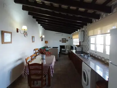 a kitchen and living room with a table and chairs at Hacienda los Majadales in Conil de la Frontera