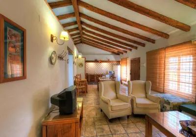 a living room with chairs and a tv and a table at Hacienda los Majadales in Conil de la Frontera