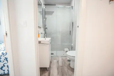 a white bathroom with a shower and a toilet at Baylight Retreat Apartment in El Puerto de Santa María