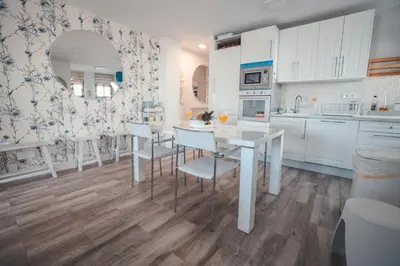 a kitchen with white cabinets and a table and chairs at Baylight Retreat Apartment in El Puerto de Santa María
