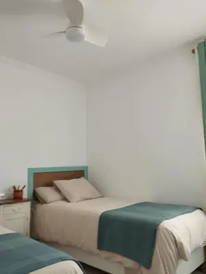 a bedroom with two beds and a white wall at LA PONDEROSA BEACH in Sanlúcar de Barrameda