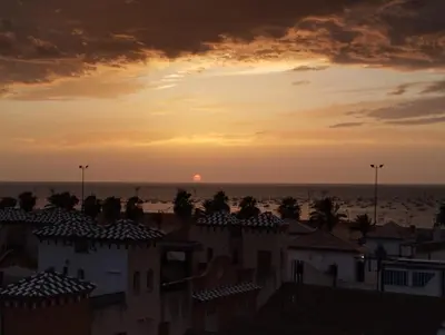 a sunset over a city with houses and the ocean at LA PONDEROSA BEACH in Sanlúcar de Barrameda