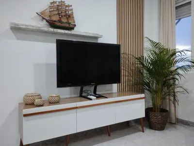 a flat screen tv sitting on top of a white cabinet at LA PONDEROSA BEACH in Sanlúcar de Barrameda