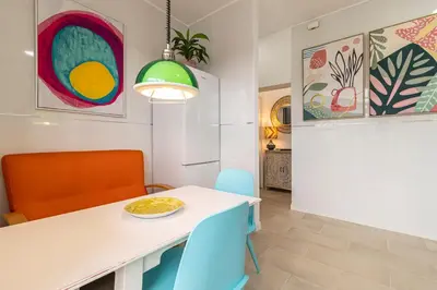 a dining room with a white table and blue chairs at El Balcón de la Bodega - Luxurious apartment in Jerez with gym in Jerez de la Frontera
