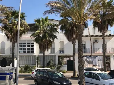 a parking lot with palm trees in front of a building at Dúplex 4, primera línea de Playa in Sanlúcar de Barrameda