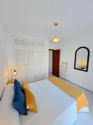 a bedroom with a large bed with blue and yellow pillows at Dúplex 4, primera línea de Playa in Sanlúcar de Barrameda