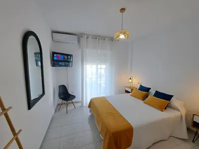 a bedroom with a bed and a mirror and a chair at Dúplex 4, primera línea de Playa in Sanlúcar de Barrameda