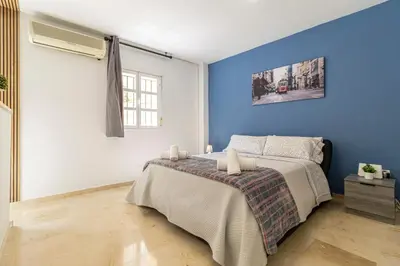 a bedroom with a bed and a blue wall at Sherry Suite Apartment - City Center in Jerez de la Frontera