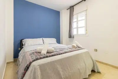 a bedroom with a bed with a blue wall at Sherry Suite Apartment - City Center in Jerez de la Frontera