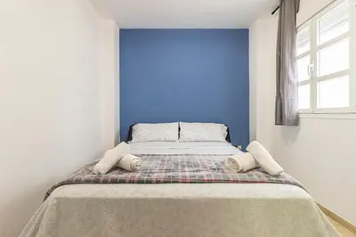 a bed in a room with a blue wall at Sherry Suite Apartment - City Center in Jerez de la Frontera