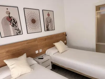 two beds in a room with pictures on the wall at Hostal Merino Jédula in Jedula