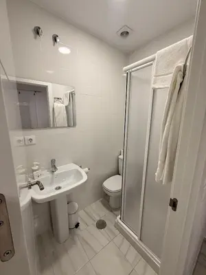 a white bathroom with a toilet and a sink at Hostal Merino Jédula in Jedula