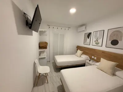 a small room with two beds and a television at Hostal Merino Jédula in Jedula