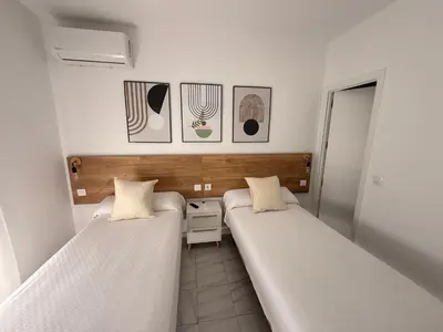 a room with two beds and a night stand in it at Hostal Merino Jédula in Jedula
