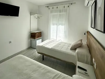 a bedroom with two beds and a tv and a window at Hostal Merino Jédula in Jedula