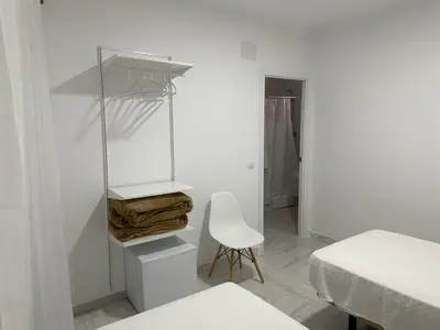 a white room with a white chair and a bed at Hostal Merino Jédula in Jedula