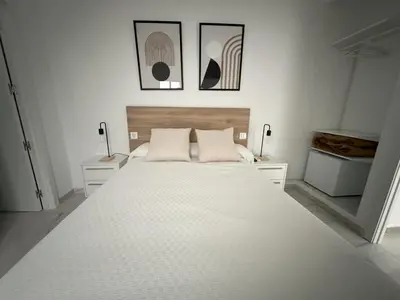 a bedroom with a large white bed with three pictures on the wall at Hostal Merino Jédula in Jedula