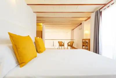 a bedroom with a large white bed with yellow pillows at Apartamentos Sherry Center in Jerez de la Frontera