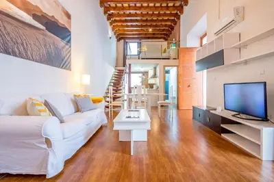 a living room with a white couch and a tv at Apartamentos Sherry Center in Jerez de la Frontera
