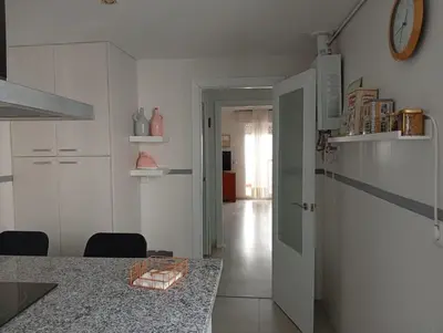 a kitchen with white cabinets and a table and a clock at Ático con impresionantes vistas in El Puerto de Santa María