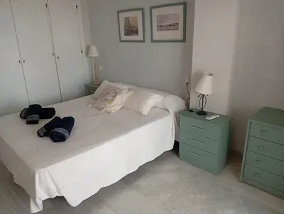 a bedroom with a white bed and a green dresser at Ático con impresionantes vistas in El Puerto de Santa María