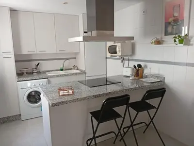 a kitchen with two black chairs at a counter at Ático con impresionantes vistas in El Puerto de Santa María