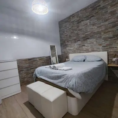 a bedroom with a bed and a brick wall at Jacuzzi Amazonas Relax en el Corazón del Puerto in El Puerto de Santa María