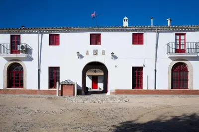 a white building with red windows and a red door at CORTIJO RURAL LA MARISCALA in Jerez de la Frontera
