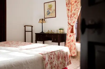 a bedroom with a bed and a table and a window at CORTIJO RURAL LA MARISCALA in Jerez de la Frontera
