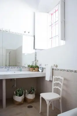 a bathroom with a sink and a chair and a mirror at CORTIJO RURAL LA MARISCALA in Jerez de la Frontera