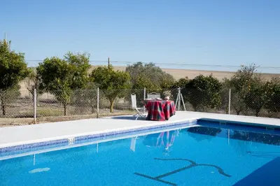 a swimming pool with a table and two chairs at CORTIJO RURAL LA MARISCALA in Jerez de la Frontera