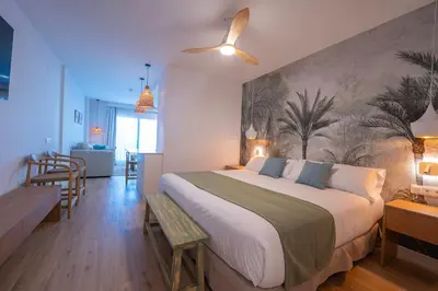 a bedroom with a large bed with a painting on the wall at Punta Candor Suites in Rota
